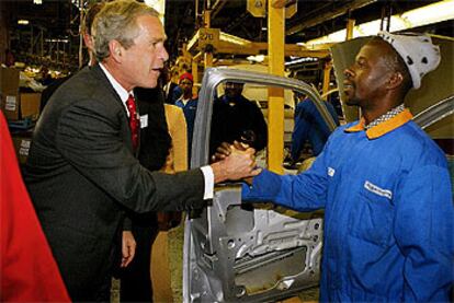 George Bush saluda a un obrero de una fábrica de automóviles Ford en Pretoria.