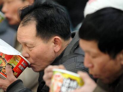 Vários passageiros comem macarrão instantâneo na estação de trem de Shenyang.