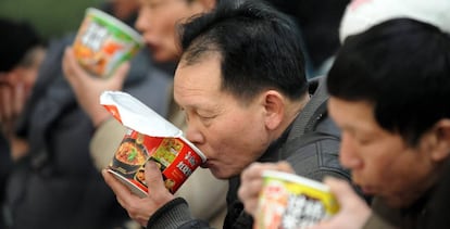 Vários passageiros comem macarrão instantâneo na estação de trem de Shenyang.