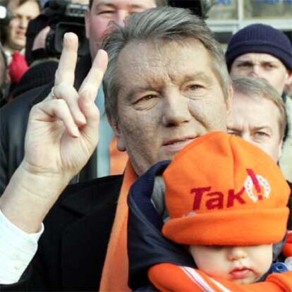 El candidato liberal Víktor Yúshenko hace la señal de la victoria con su hijo Taras en los brazos, después de votar en Kiev.