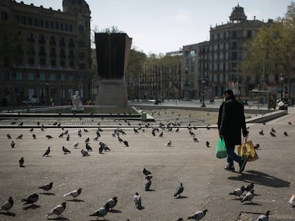 Una persona camina cargado con la compra por plaza Catalunya donde solo quedan las palomas.
