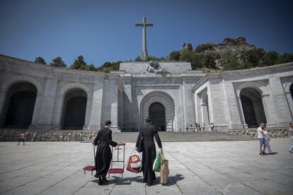 Dos sacerdotes con sotana entran con reclinatorios en la Basílica del Valle de los Caídos, en San Lorenzo de El Escorial, el día en el que el Gobierno socialista haya aprobado el decreto que cambia un artículo de la Ley de la Memoria Histórica que reserva el lugar sólo para los restos mortales de personas fallecidas a consecuencia de la Guerra Civil.