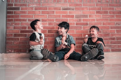 Tres niños se ríen, mientras comen un helado.