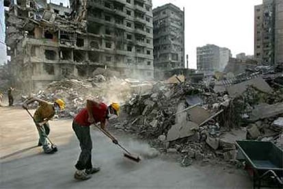 Partidarios de Hezbolá barren una calle en un área residencial destruida al sur de Beirut.