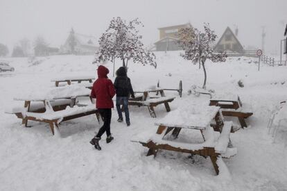 Esta bajada casi general de las temperaturas será más acusada en las mínimas que se situarán por debajo de los 10º grados en casi toda la Península, según informa AEMET. En la imágen, dos personas caminan entre las mesas de un merendero cubierto de nieve en el Puerto de San Isidro (León).