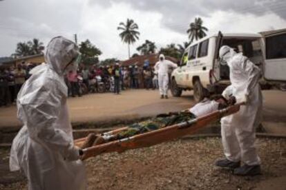 Dos enfermeros transportan a un enfermo de ébola en Sierra Leona.