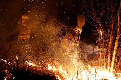 Dos bomberos participan en las labores de extinción del incendio que se ha producido en los alrededores de Labares, Asturias.