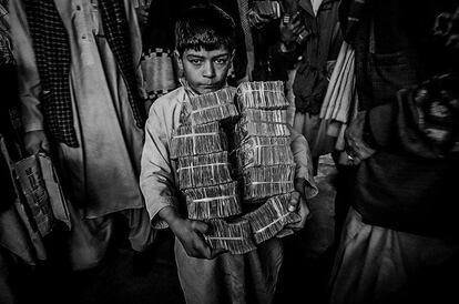 Un niño transporta una pila de dinero en el mercado de intercambio en Herat, al oeste de Afganistán, en 2001.