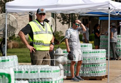 People stand by cases of bottled water as the City of Germantown gives them out to residents on Monday, July 24, 2023