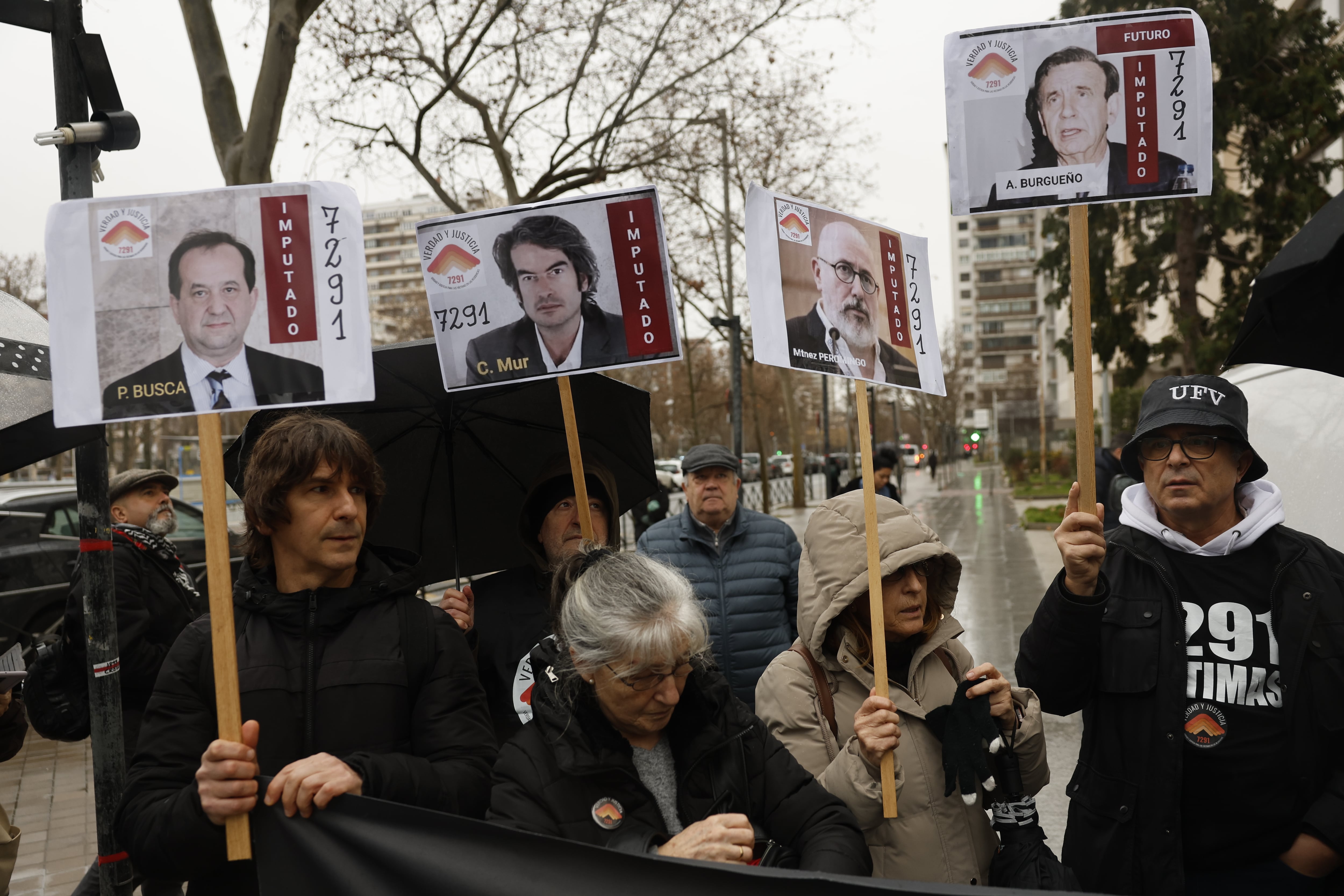 Varios manifestantes sostienen carteles con los rostros de los cuatro exresponsables imputados, Pablo Busca, Carlos Mur, Javier Martínez Peromingo y Antonio Burgueño, este lunes a las puertas de los juzgados de Plaza de Castilla, en Madrid.