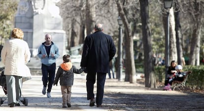 Unos abuelos pasean con su nieto por el parque.