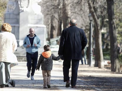 Unos abuelos pasean con su nieto por el parque.