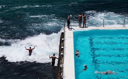 Dos nadadores entran en el mar mientras otras buscan alivio de la ola de calor en una piscina de agua salada en Sídney (Australia).