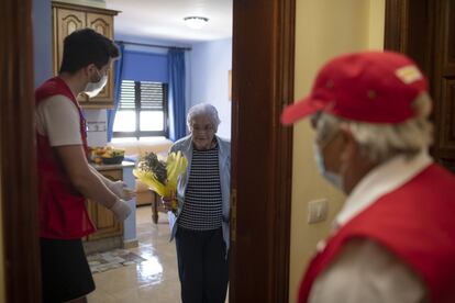 Dos voluntarios de la Cruz Roja llevan flores a madres por el Día de la Madre, en La Gomera. 