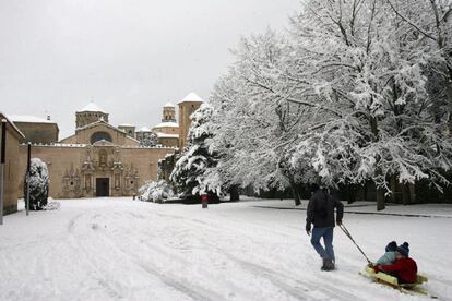 Un hombre juega con sus hijos en la nieve ante el Monasterio de Poblet, Tarragona.