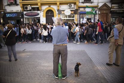 Un hombre mira la manifestación de estudiantes en una calle de Sevilla. 

