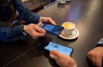 Un camarero revisa el certificado vacunal de una clienta en un bar de San Sebastián.