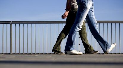 Dos personas caminan por el paseo mar&iacute;timo de Barcelona.