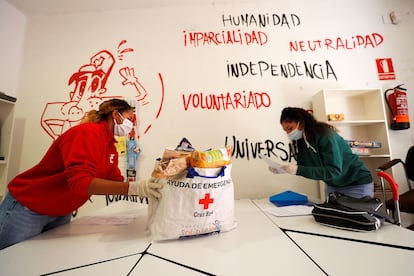 Una voluntaria de Cruz Roja entrega una bolsa con productos de primera necesidad a una joven.