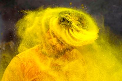 Un hombre sacude la cabeza llena de polvo de color amarillo durante el festival Holi en Prayagraj, la India, el martes.