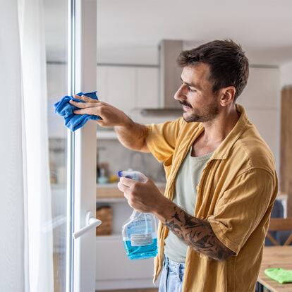 Un chico limpiando las ventanas de sus casa.