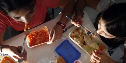 Dos ni&ntilde;as comen comida preparada en casa.