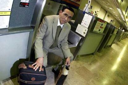 Rafael Villalba, con su equipaje, espera sentado en uno de los mostradores de facturación de la terminal T-1 del aeropuerto de Barajas.