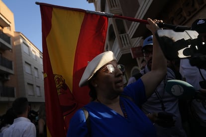 Una manifestante porta una bandera española con el sagrado corazón de Jesús.