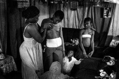 Veronica, de 28 años, masajea los pechos de Michelle, su hija de 10 años, mientras los otros hijos la miran. Bafoussam, Camerún. De la exposición 'Belleza prohibida'