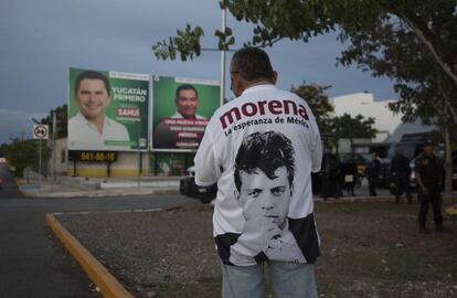 Un simpatizante de Morena frente a propaganda del PRI en Mérida, Yucatán.
