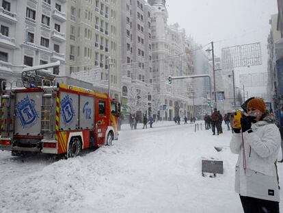 Varias personas pasean por la Gran Via cubierta de nieve en Madrid, este sábado.