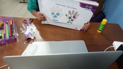 Un niño muestra un trabajo a su maestra a través de una videollamada.