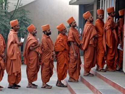 Los santos hindúes hacen cola en una local de votación durante la última fase de la elección de la asamblea estatal de Gujarat a las afueras de Ahmedabad, India.