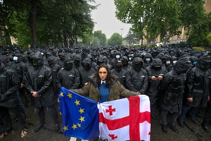 Una mujer sujeta una bandera nacional y otra europea ante los agentes de policía que rodean el Parlamento, este martes en en Tbilisi (Georgia).