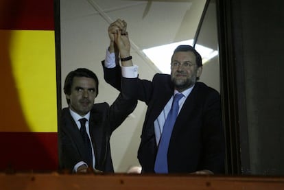 José María Aznar (izquierda) y Mariano Rajoy (derecha) saludan a los simpatizantes del PP desde la ventana de la sede del PP de Madrid, tras los resultados de las elecciones generales del 14-M de 2000.