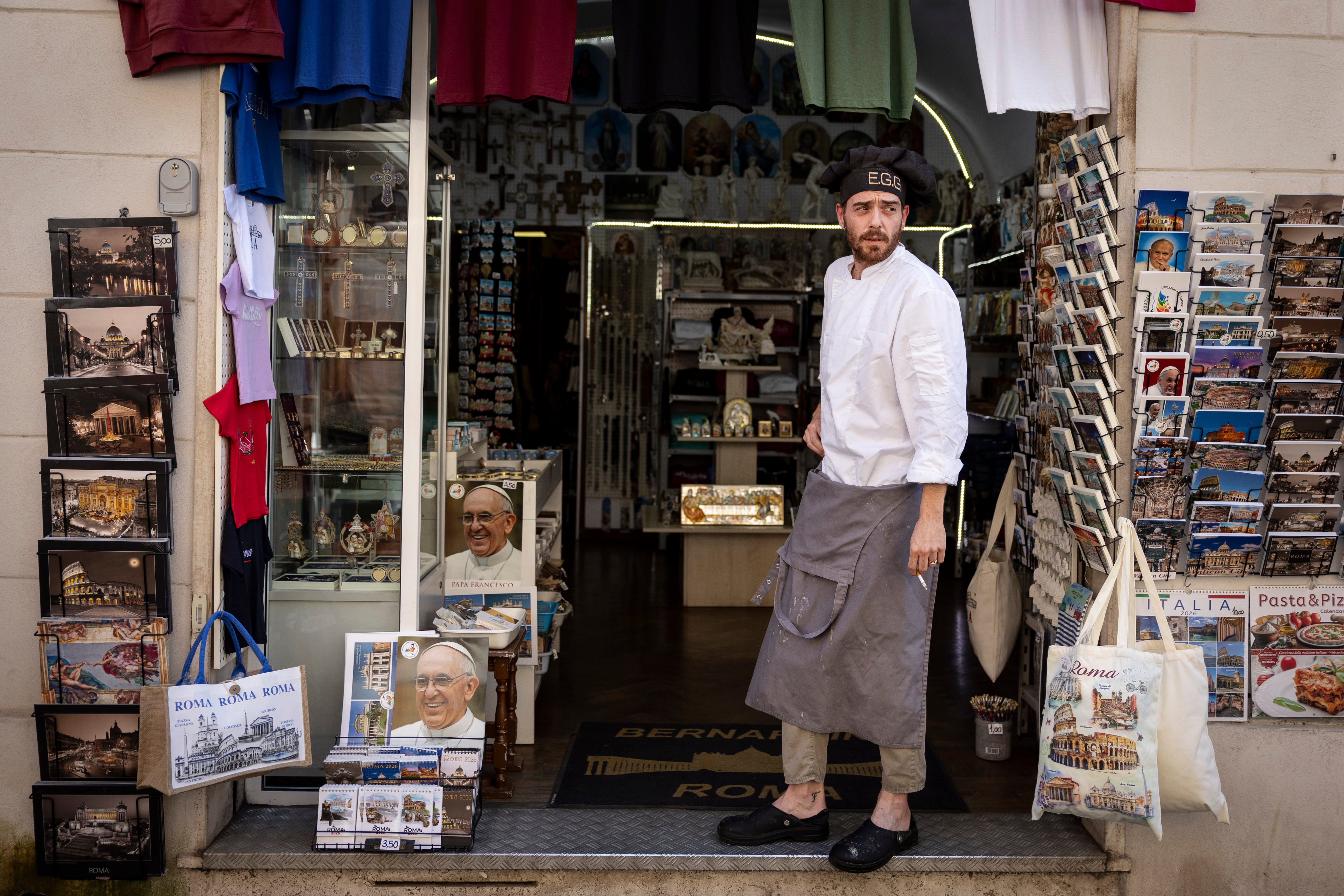 Un cocinero descansa en la entrada de una tienda de la famosa calle Borgo Pio, al lado de la plaza de San Pedro del Vaticano.