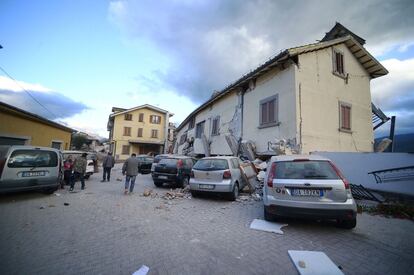 Um grupo de moradores caminha por uma das ruas da cidade italiana de Amatrice com edifícios destruídos.