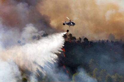 Un helicóptero lanza agua el sábado sobre el incendio que se originó en el municipio de Cortes de Pallás. La Generalitat valenciana ha asegurado que más de 40 medio aéreos trabajan en la extinción de este fuego y el de Andilla.