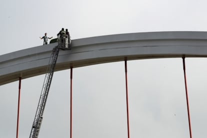 Un hombre desempleado protesta por su situación laboral en el puente sevillano de la Barqueta.