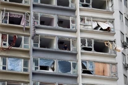 Un hombre mira desde su bloque de apartamentos en el que las ventanas han sido destruidas debido al tifón Hato, en Macao (China).