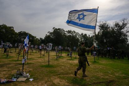 Un militar israelí ondea una bandera de Israel en un memorial para las personas asesinadas y secuestradas por durante el ataque de Hamás en el festival Super Nova. 