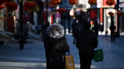 Una mujer pasea por Pekín con una máscarilla para prevenir el contagio del coronavirus.