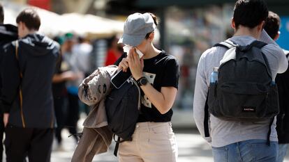 Una persona se limpia la nariz en las Ramblas de Barcelona.