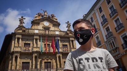 Un niño con mascarilla posa delante del Ayuntamiento de Pamplona, durante el primer fin de semana de fase 2 en la desescalada de la pandemia por covid-19.