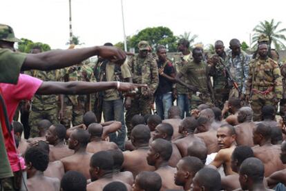 Soldados del presidente Ouattara señalan a unos hombres que aseguran reconocer entre decenas de prisioneros capturados en combates y patrullas en Abiyán.