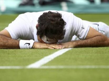 Federer, tendido sobre el c&eacute;sped de la pista central de Wimbledon.