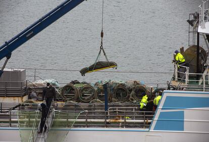 Operarios bajan con la ayuda de una grúa a una de las personas fallecidas en el naufragio del buque gallego, a su llegada al puerto de San Juan de Terranova, este sábado.