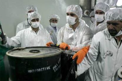 Técnicos nucleares iraníes, junto a un bidón con productos radiactivos ayer en la central nuclear de Isfahán.