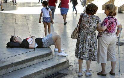 Un turista descansa a la sombra, en la Plaza de la Virgen de Valencia.