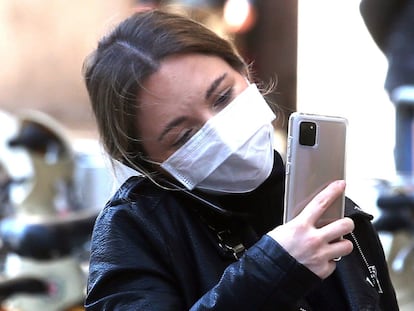 Milan (Italy), 24/02/2020.- A woman wearing a protective face mask uses a mobile phone, in the center of Milan, northern Italy, 24 February 2020. Italian authorities announced on the day that there are over 200 confirmed cases of COVID-19 disease in the country, with at least five deaths. Precautionary measures and ordinances to tackle the spreading of the deadly virus included the closure of schools, gyms, museums and cinemas in the affected areas in northern Italy.